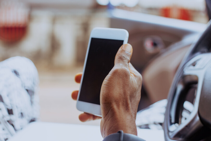 Cropped Hand Of Black Man Using Mobile Phone In Car