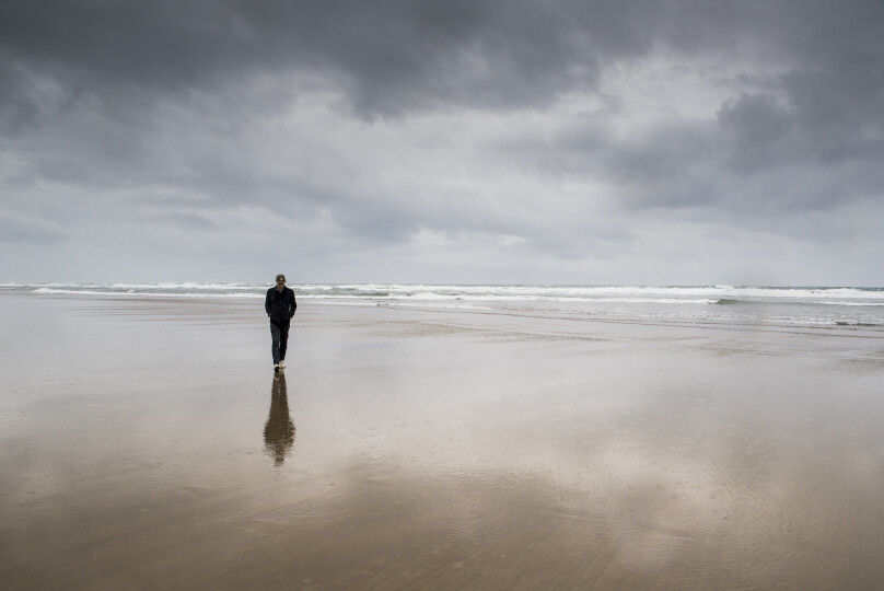 Man-walking-at-beach-against-cloudy-sky_GettyimagesCavanImages
