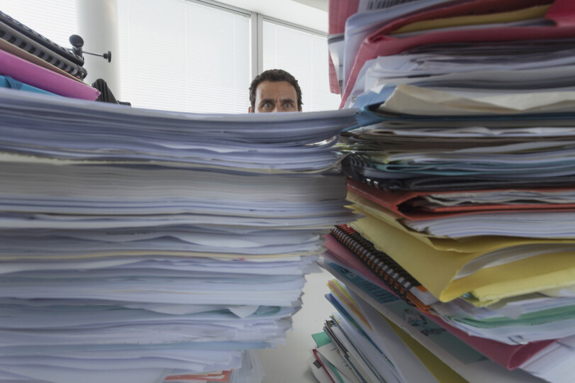 Man-surrounded-by-piles-of-files-in-office_GettyimagesPaulHarizan