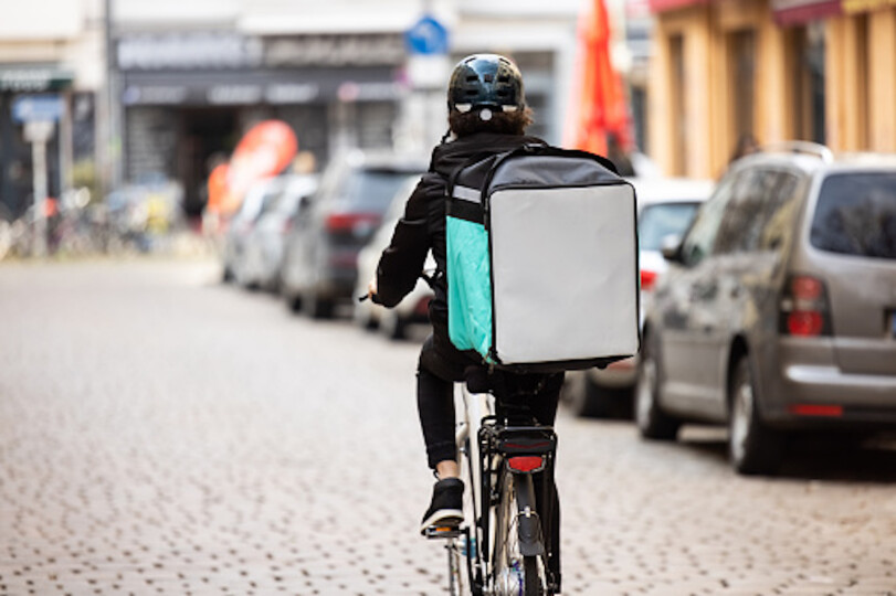 Delivery-person-with-thermal-box-on-a-bicycle-in-town_GettyimagesLuis-Alvarez