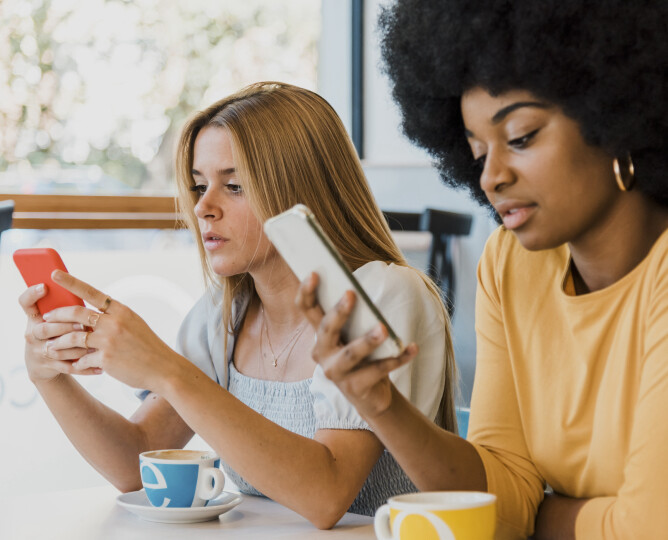 Diverse-girlfriends-using-cellphones-in-cafe_Gettyimages