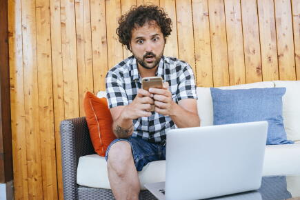 urprised-man-looking-at-the-mobile-phone-in-the-backyard-of-the-house_GettyimagesF.J.-Jimenez
