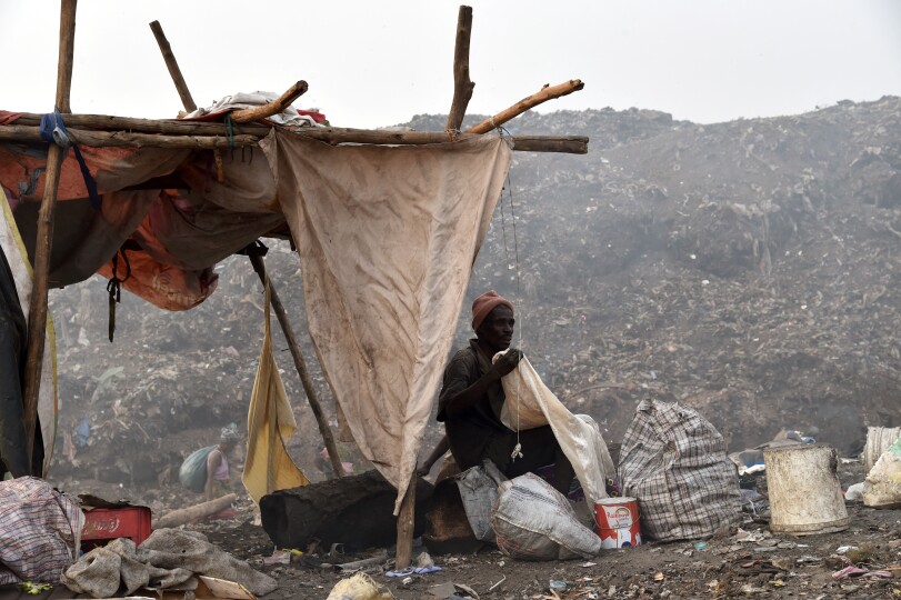 A man sits by a shelter as he searches for valuables in a rubbish dump in Freetown on March 28, 2018. - Sierra Leone's economy is in a dire state following the 2014-16 Ebola crisis and a commodity price slump that drove away foreign investors, and living conditions are among the poorest in the world. (Photo by ISSOUF SANOGO / AFP)