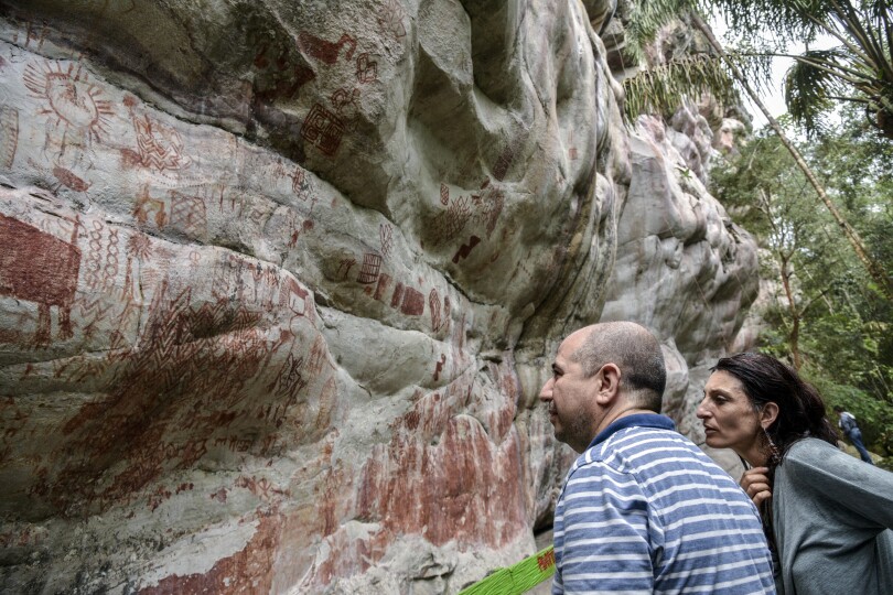 Celine Valadeau (R), an anthropologist from the French Institute of Andean Studies (IFEA), and Ernesto Montenegro (L), director of the Colombian Institute of Anthropology and History, look at rock art on the Raudal de Guayabero hill in the Serrania La Lindosa in the Amazonian department of Guaviare, Colombia, on June 8, 2018. - The Serrania La Lindosa, declared as a new Protected Archaeological Site of Colombia, is one of the places with the most abundant rock art in the world. The Serranias of Chiribiquete and La Lindosa are among the areas in Colombia that were closed to outsiders during the armed conflict and are now opening up to scientific researchers. (Photo by GUILLERMO LEGARIA / AFP)