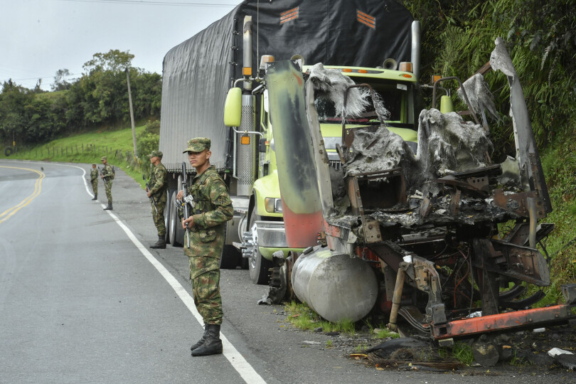 Soldiers stand guard next to a truck burnt by members of the Clan del Golfo drug cartel, on a road near Yarumal, Antioquia department, Colombia, on May 6, 2022. - The criminal gang Clan del Golfo announced a five-day armed strike in retaliation for the extradition to the United States of drug lord Dairo Antonio Usuga, alias 'Otoniel', who until a few months ago was the head of that organization. (Photo by JOAQUIN SARMIENTO / AFP)