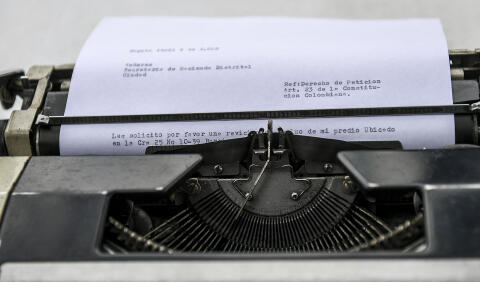 Street clerk Flavio Cesar Pinilla, 68, types a letter for a client in front of the district taxing office in Bogota, on April 9, 2018. - Street clerks are experts in filling out forms, documents and even in typing letters, to help their clients with paperwork. (Photo by Luis ACOSTA / AFP)