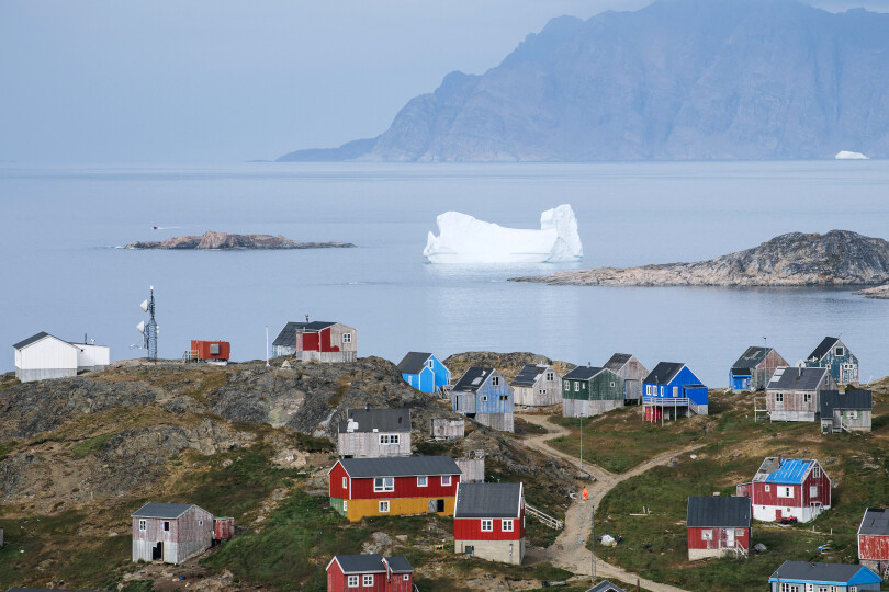 A picture taken on August 19, 2019 shows icebergs floating near the coast behind colourful houses in Kulusuk (aslo spelled Qulusuk), a settlement in the Sermersooq municipality located on the island of the same name on the southeastern shore of Greenland. (Photo by Jonathan NACKSTRAND / AFP)