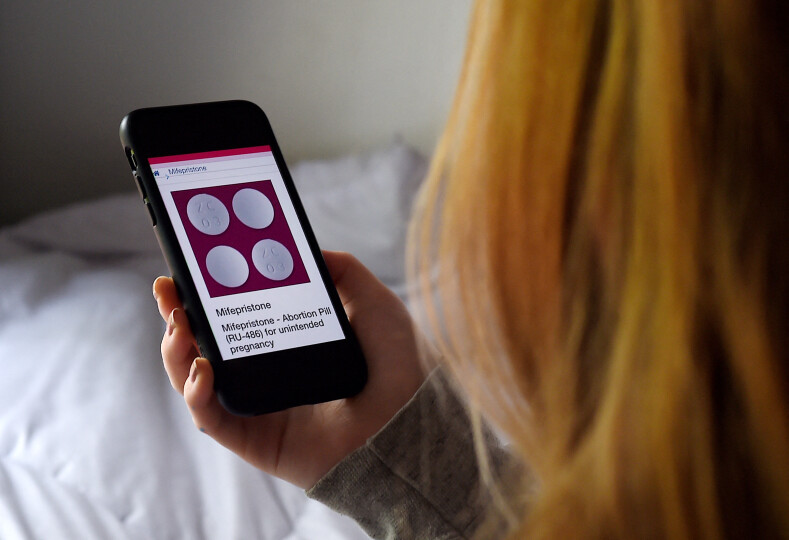 In this photo illustration, a person looks at an Abortion Pill (RU-486) for unintended pregnancy from Mifepristone displayed on a smartphone on May 8, 2020, in Arlington, Virginia. - One week after Sally realized she was pregnant, her home state Texas temporarily banned abortions, deeming them unnecessary elective procedures that were suspended because of the coronavirus crisis.So, the 34-year-old, whose name has been changed for this story to protect her privacy, took matters into her own hands -- something she never would have considered in the past. Having split with her boyfriend, she decided to buy pills on the internet, and perform her own abortion at home. (Photo by Olivier DOULIERY / AFP)