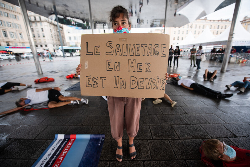 An activisits of NGO SOS Mediterranee holds a placard reading "Rescue at sea is a duty" under in the Ombriere installation during a "die-in" happening on the Old Port of Marseille, southeastern France, August 29, 2020, during a demonstration to demand the release by Italian authorities of the NGO's rescue ship Ocean Viking. - The migrant rescue ship Ocean Viking was detained and immobilised by Italian authorities on July 22, 2020, over technical irregularities, a move blasted as "harassment" by the charity that runs the vessel. (Photo by CLEMENT MAHOUDEAU / AFP)