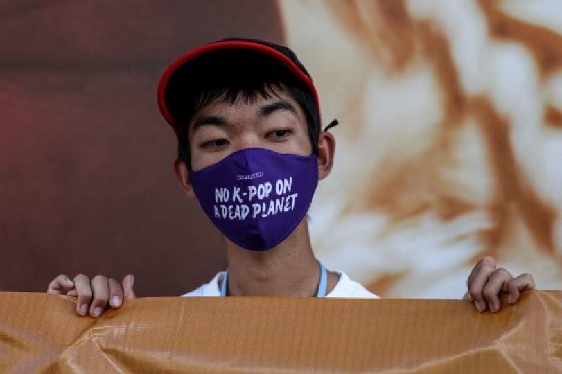 Un militant climatique sud-coréen portant un masque « pas de K-pop sur une planète morte » manifeste au Centre de congrès international de Charm el-Cheikh, dans la ville balnéaire égyptienne du même nom sur la mer Rouge, pendant la Conférence climat COP27, le 10 novembre 2022 / AHMAD GHARABLI / AFP
