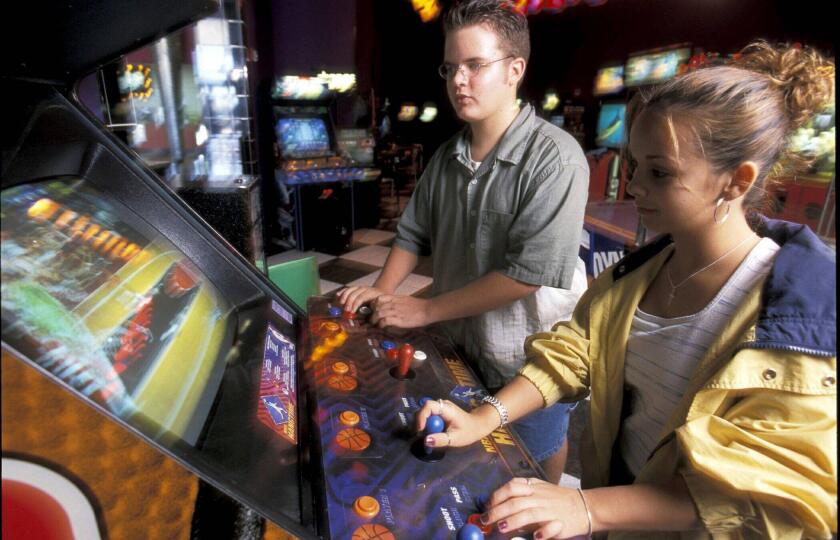 Austin Texas USA : Middle school friends play video game at arcade © Bob Daemmrich / Alamy Stock Photo